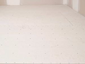 Underlay sheets are installed and evenly nailed to the floor   Image Description: The image shows a room with underlay sheets securely fastened to the floor using evenly spaced nails.