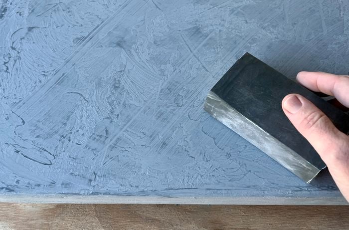 A hand using a sanding block to sand a painted door panel.