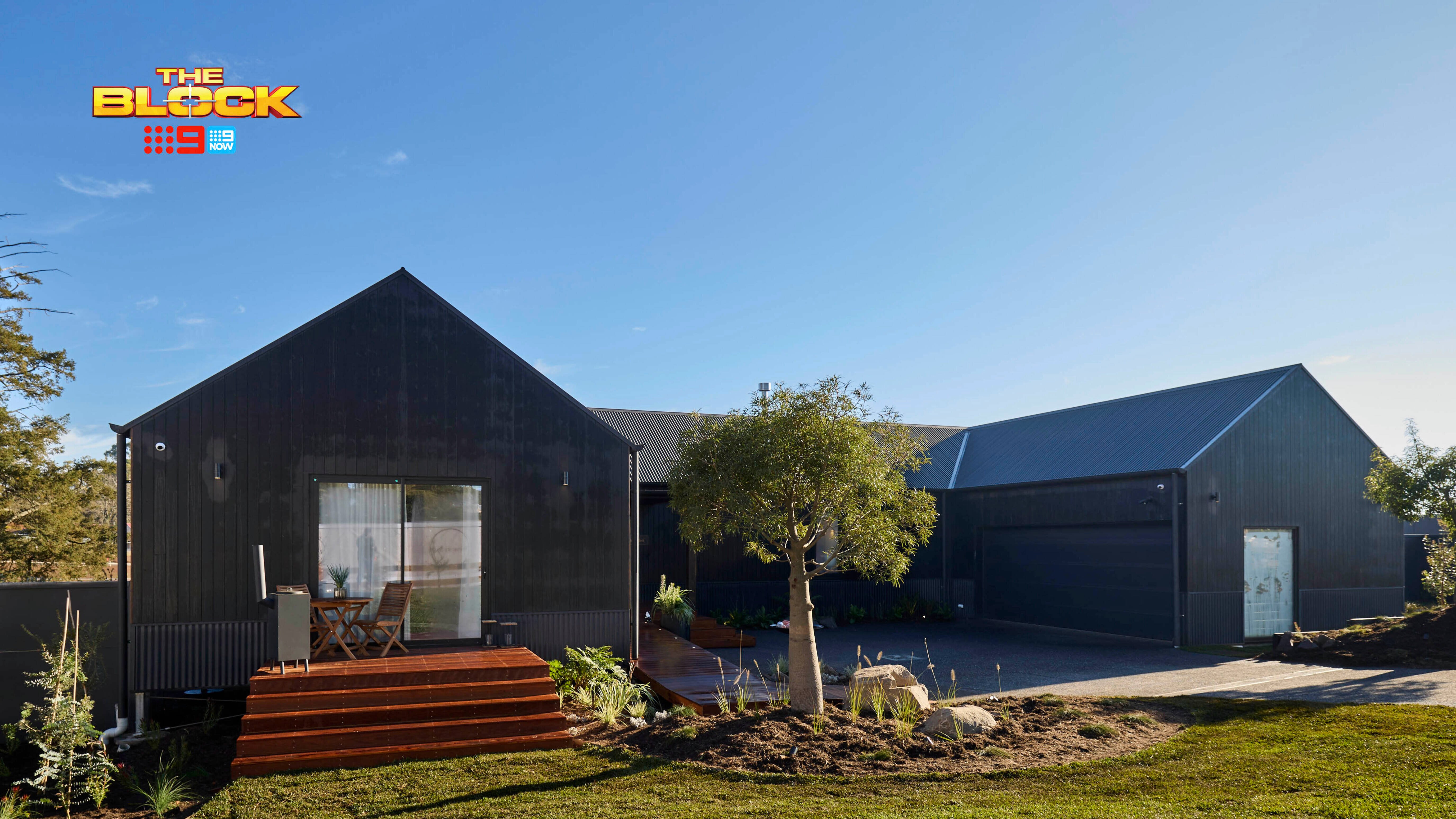 The front of a house with a grassed area, trees and a driveway in it.
