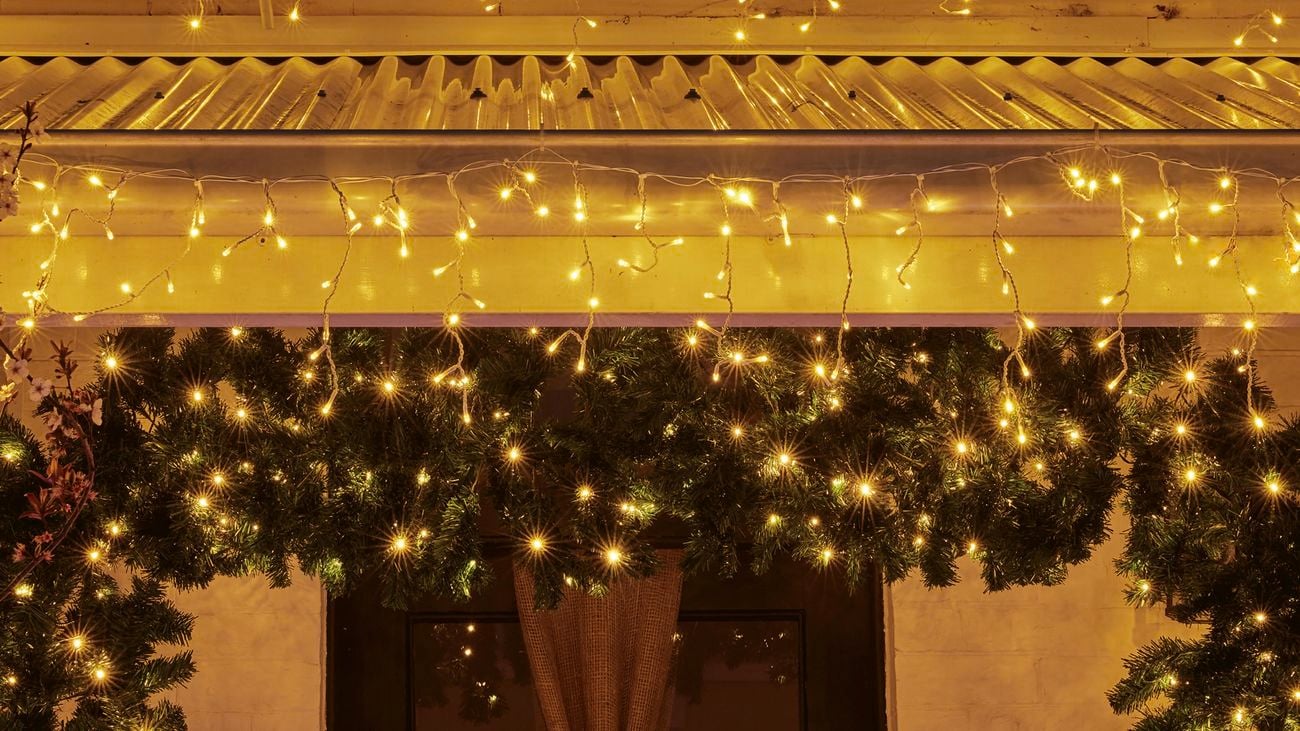 Close-up of the front door with fairy lights outlining the roof and wreath archway around the door.