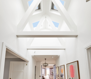 Long hallway painted white with exposed roof trusses and four skylights