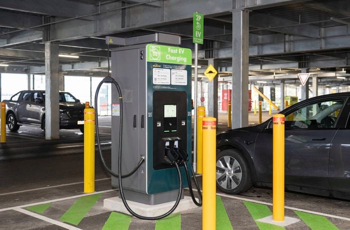  A Tesla electric vehicle is parked at a dedicated fast EV charging station in a multi-level car park, connected to an Exploren charging unit for charging. 