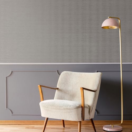White chair and a stand lamp located in front of a Boutique wallpaper wall.