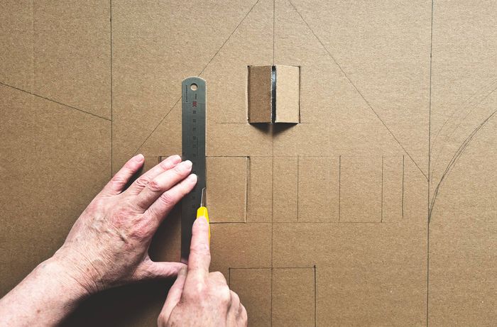 A hand using a marker to write numbers on a cardboard Advent calendar.