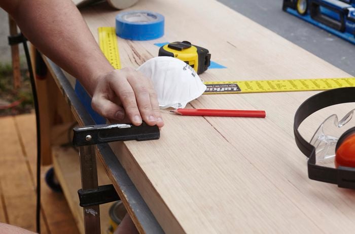 A person clamping a timber panel to a bench