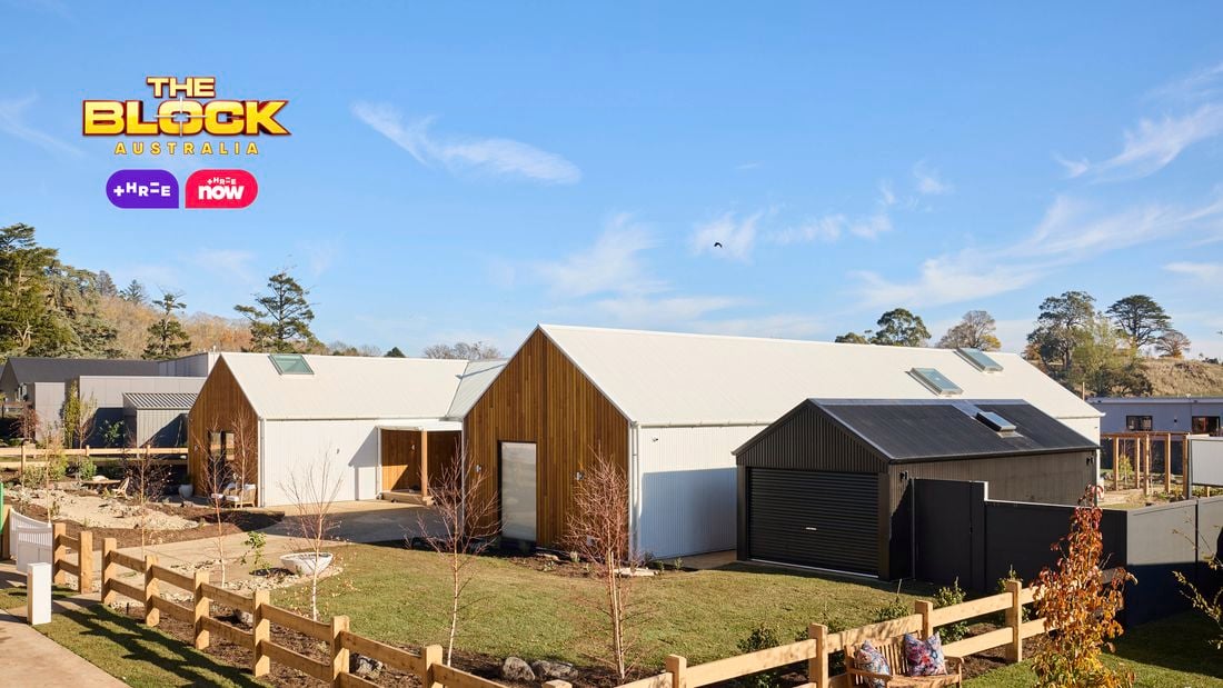 The front area of a house with a timber fence, grassed area, trees and a driveway in it.