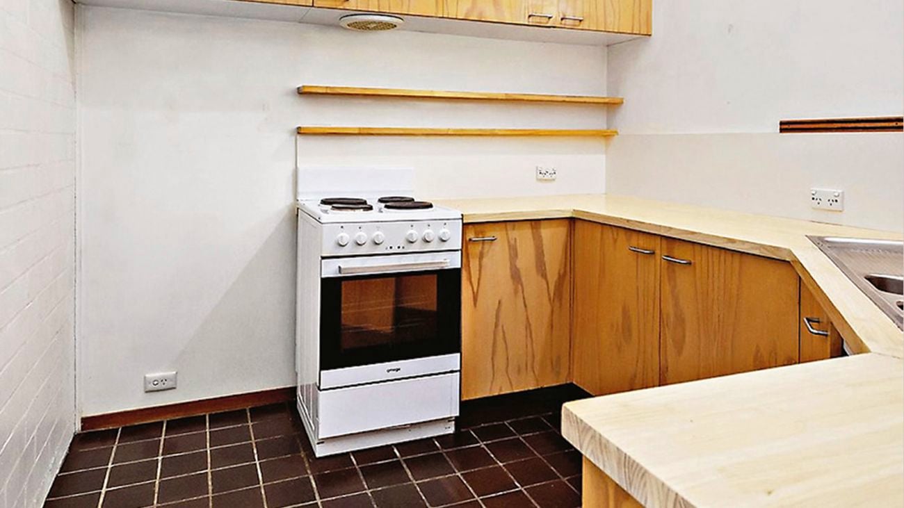 Plain kitchen that has wooden cupboards and benches with white oven in view