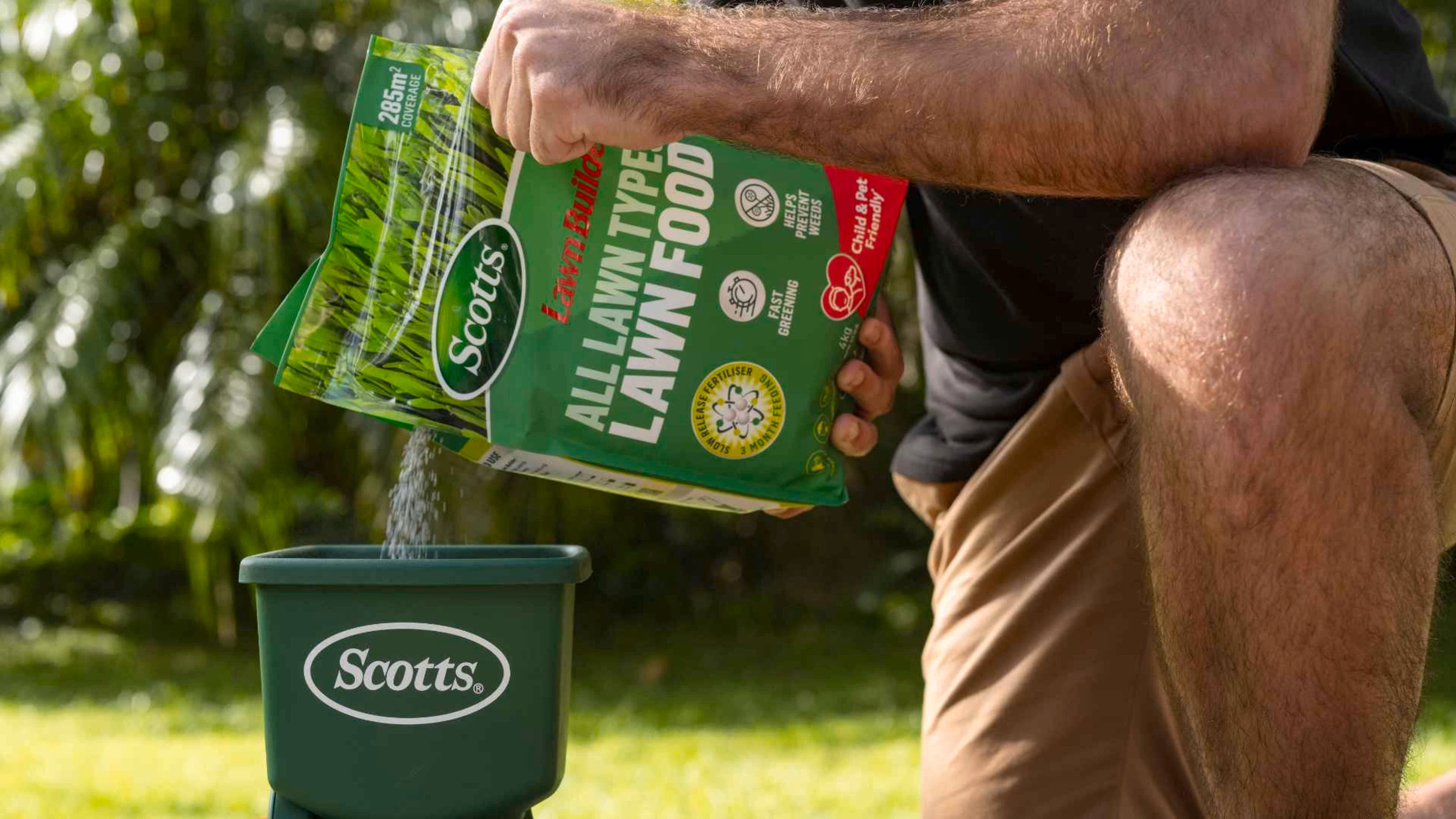 Man pouring fertiliser into spreader.