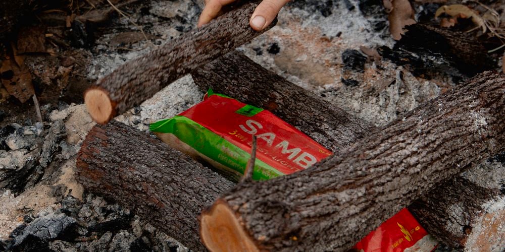 Firewood
  being stacked on top of Samba Firelog (3180823) to start campfire