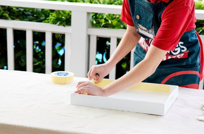A woman applies masking tape to the sides of a breakfast tray.