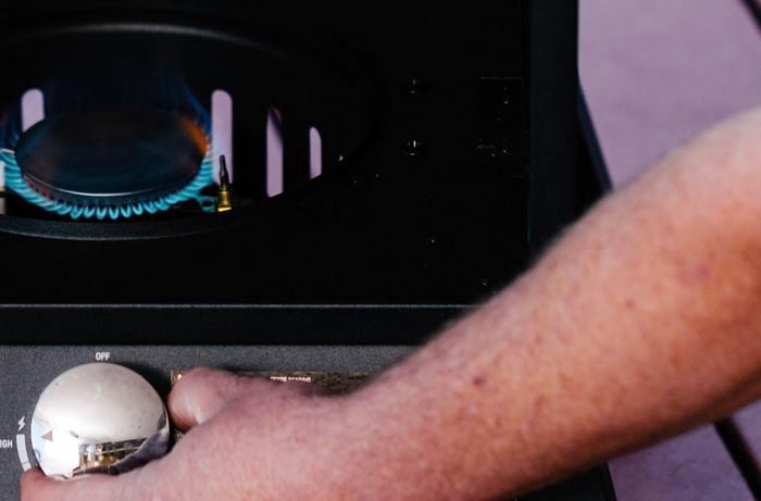 Person adjusting the heat on a vertical smoker
