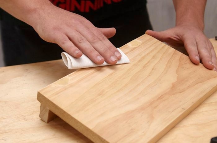 A person sanding a small timber shelf