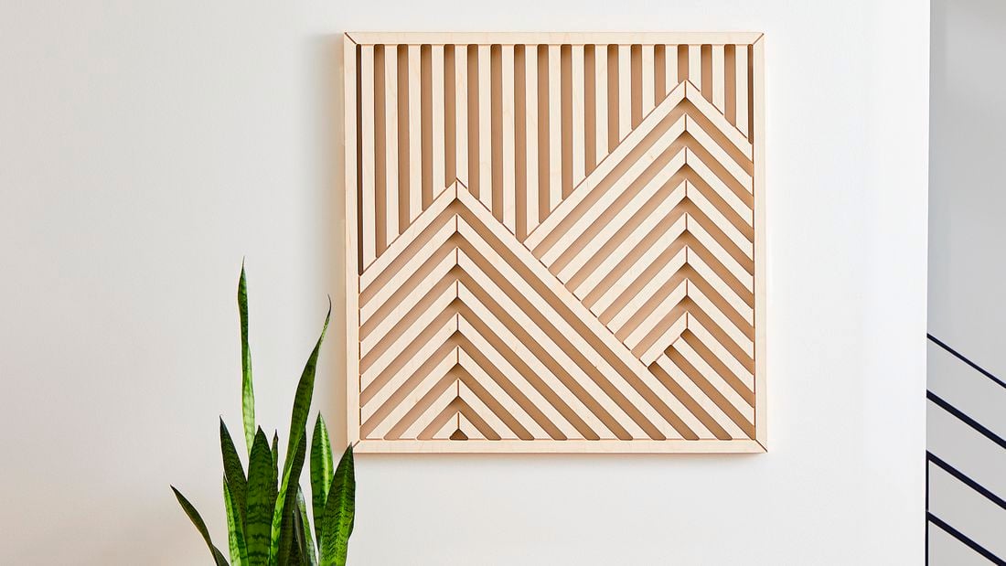 A table with a wooden top next to a wall with a plant on it and a picture hanging on the wall.