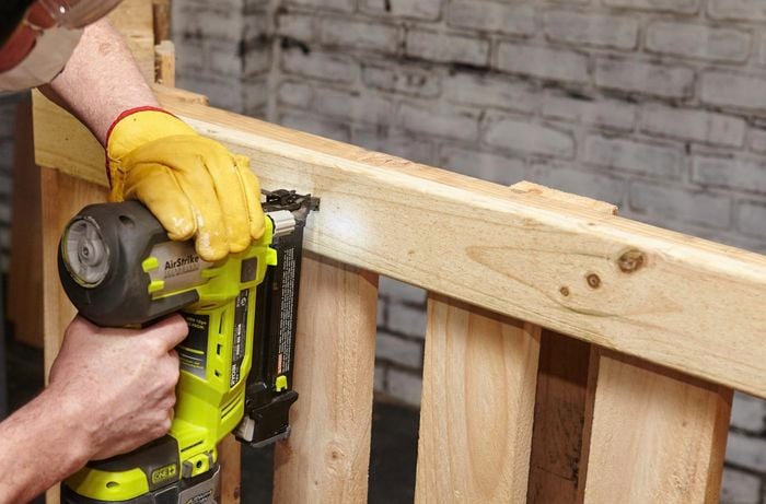 A timber support beam being nailed to a frame constructed from a wooden pallet