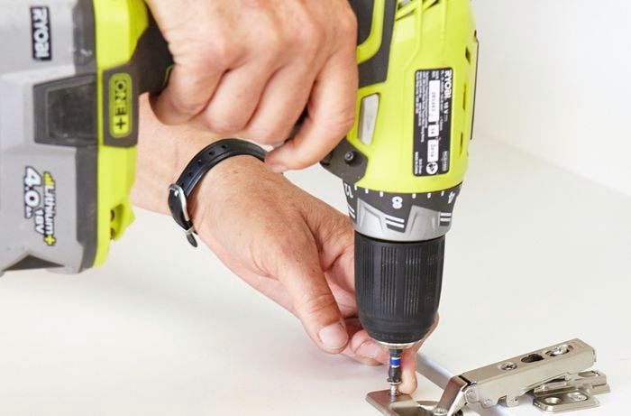 Person drilling hinge to door.