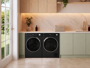 Modern laundry featuring black front-loading washing machine and dryer, sage green cabinetry, marble-look splashback and timber overhead cupboards.