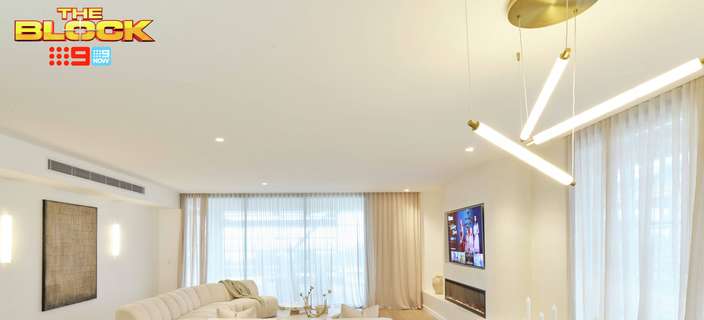 Open-plan living and dining area featuring neutral furniture, light timber flooring, floor-to-ceiling curtains and modern pendant lighting.