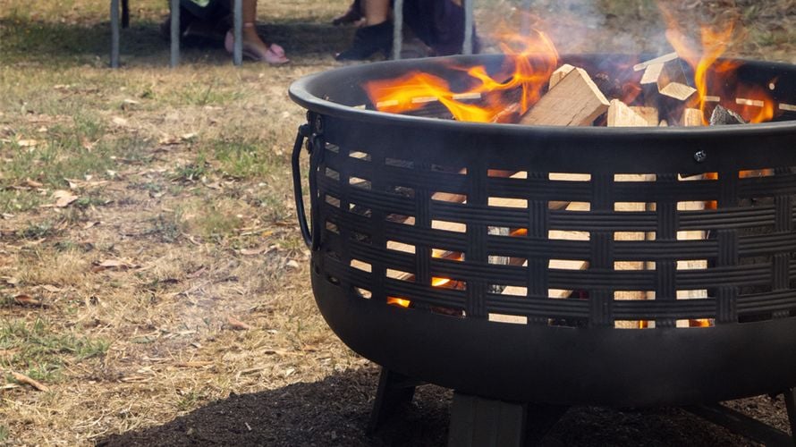A lit brazier with people seated at a table in the background