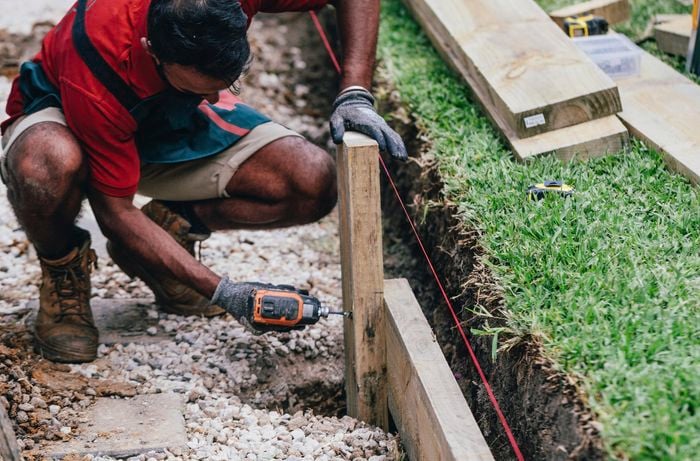 A Bunnings team member bolting a retaining wall to a vertical post