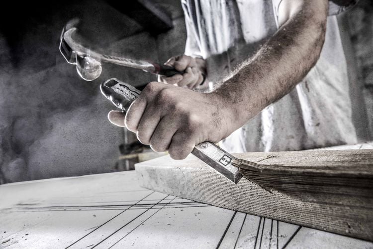 A hammer and chisel being used to shape a piece of timber