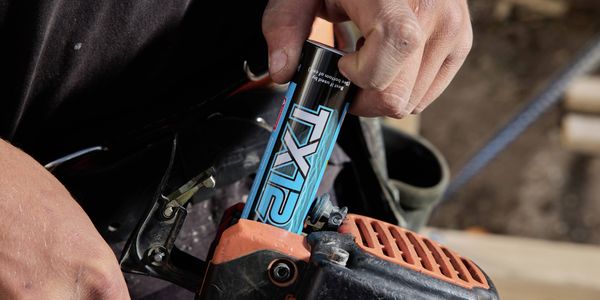 Close-up of a person inserting a TITAN fuel canister into a chainsaw.