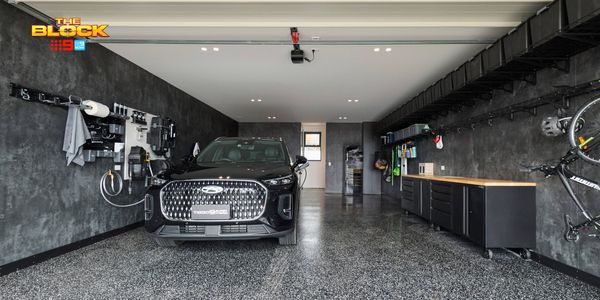 Modern garage featuring a black SUV, polished speckled flooring, wall-mounted storage, bicycles and built-in cabinetry.