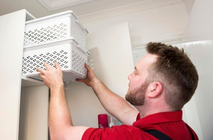 Person places stackable boxes into a cupboard