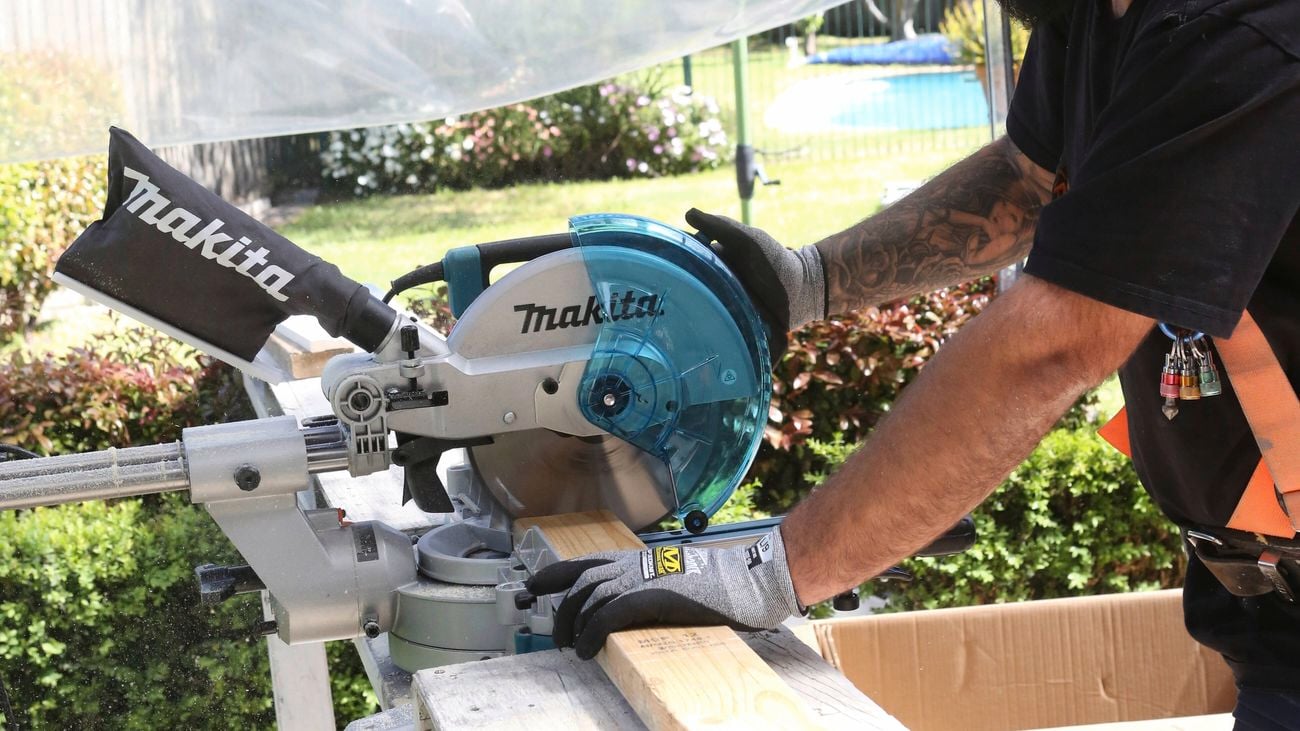 A close up image of a tradesperson wearing safety glasses and using a Makita Mitre saw