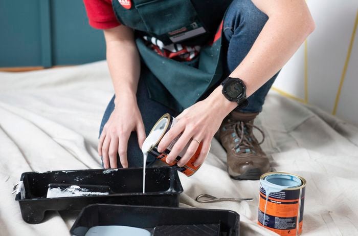Person pouring paint into a tray.