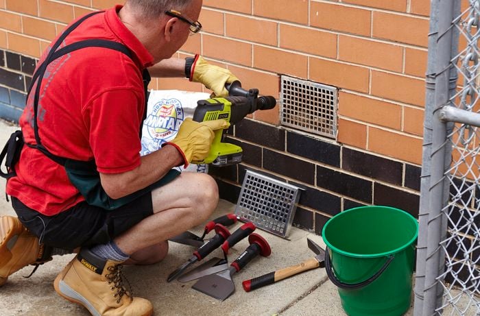 Using your hammer drill to drill through the mortar that holds the old vent in place