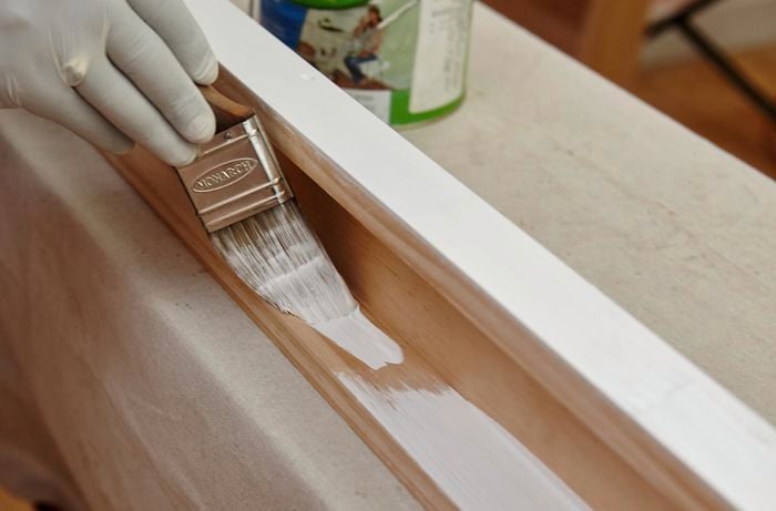 A person painting pine timber white