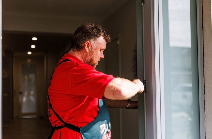 Person reattaching a door to a door frame.