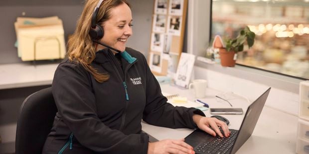 lady sitting at a desk with head phones on while using her laptop