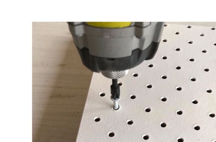 A pegboard being screwed into place with a power drill