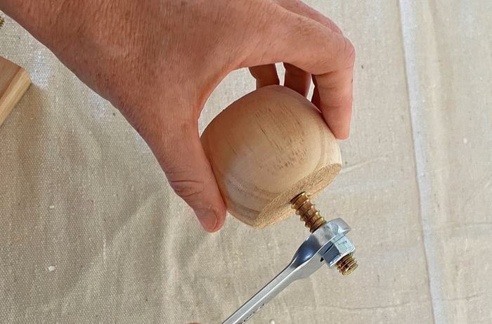 A threaded rod being removed from a bun foot using nuts and a spanner
