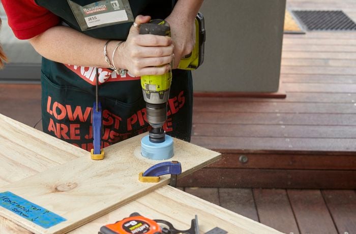 A hole being drilled into a wooden panel for a bird entryway