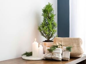 Gifts wrapped with hessian and decorated with rosemary, white candles and a mini Christmas tree.