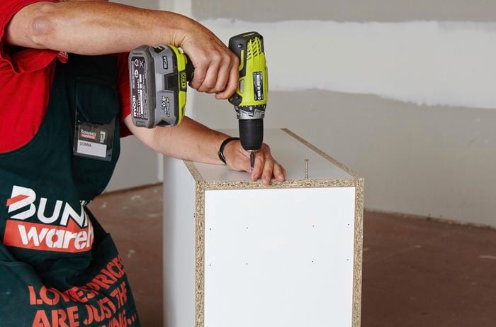 Person attaching panel of cabinet using drill