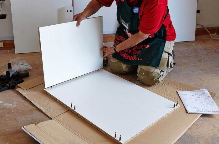 A person fitting a side panel onto pins in a back panel