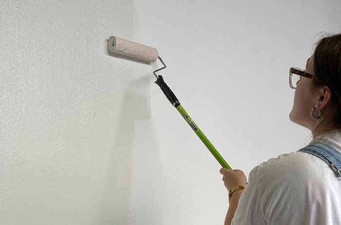 Person painting base coat with paint roller.