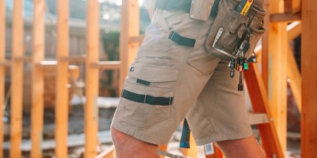A person with a tool belt on at a construction site.
