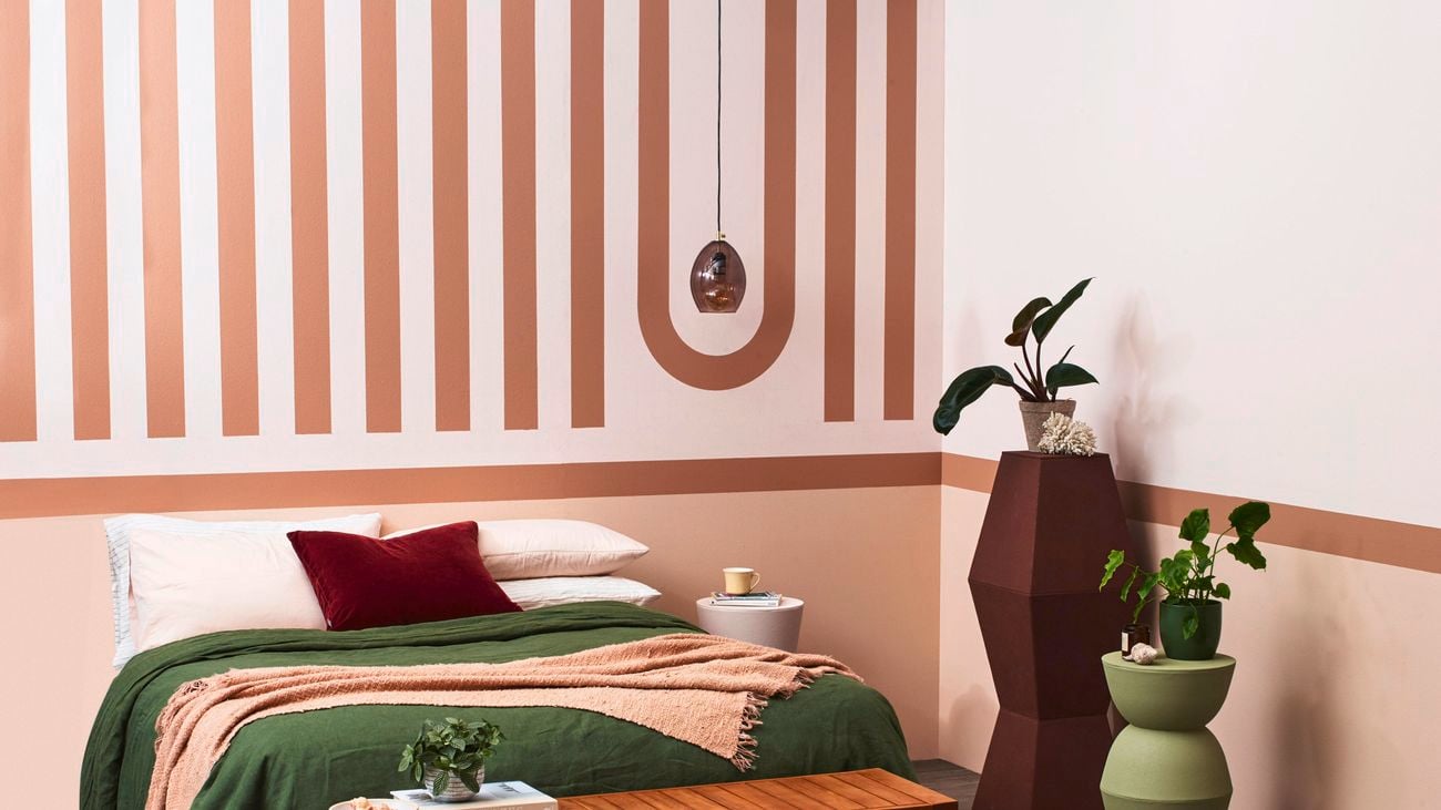 Bedroom with a bed, table and pot plants in it.