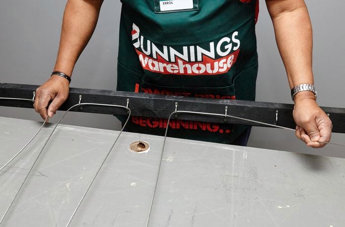 Metal wire being threaded through loops inside a timber frame