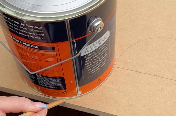 Hands drawing semi circles around paint can template