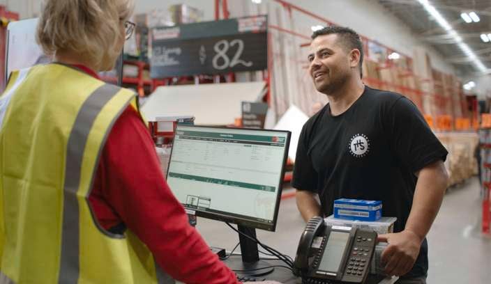bunnings team member wearing a yellow vest and serving a customer and the trade desk