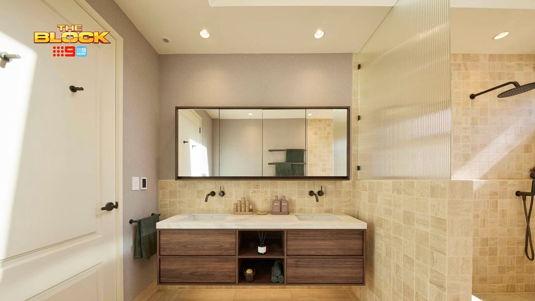 Modern bathroom with double sink vanity, large mirror, light tiles, glass shower partition, and white door with black hardware. 