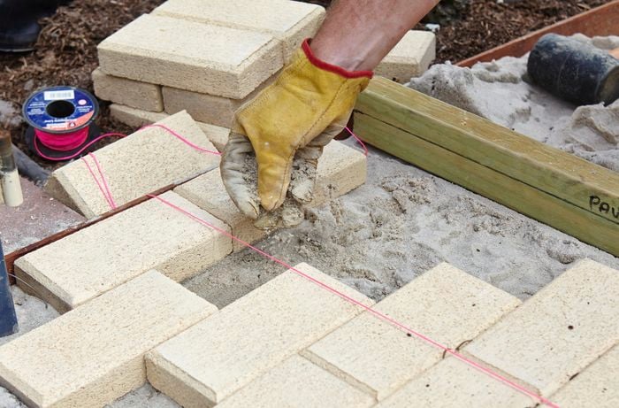 A person running a line of pink string over newly laid pavers