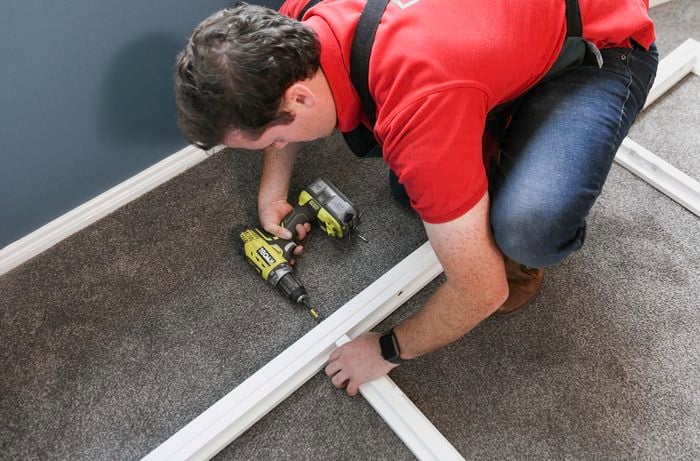Person using a cordless drill to assemble plantation shutters on the floor