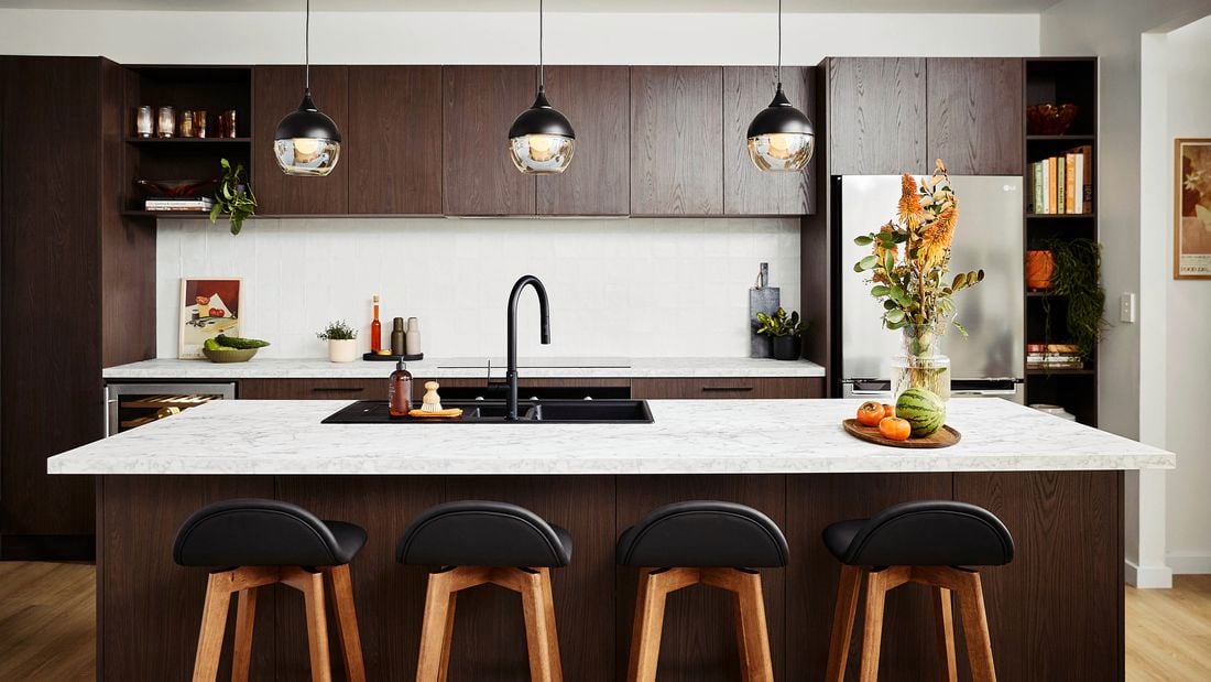 Mid Century Modern kitchen with dark wood cabinets, marble island, and retro pendant lights