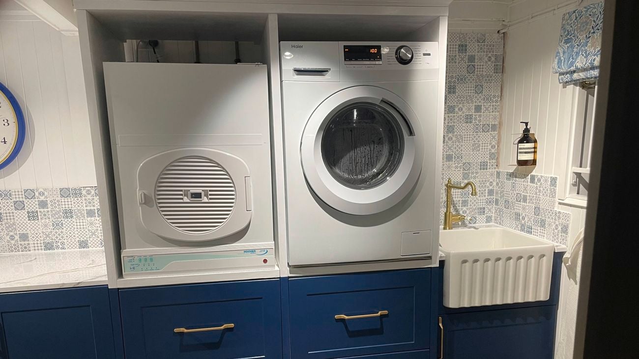 A room with blue drawers and a dryer and washing machine on top of them, in it.